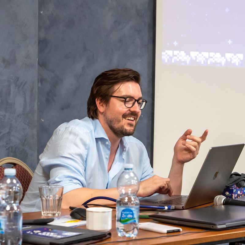Christian Wenzel lacht am Laptop während einer Präsentation