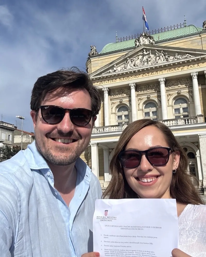 Christian Wenzel and his co-founder holding an official letter in front of a theatre in Croatia