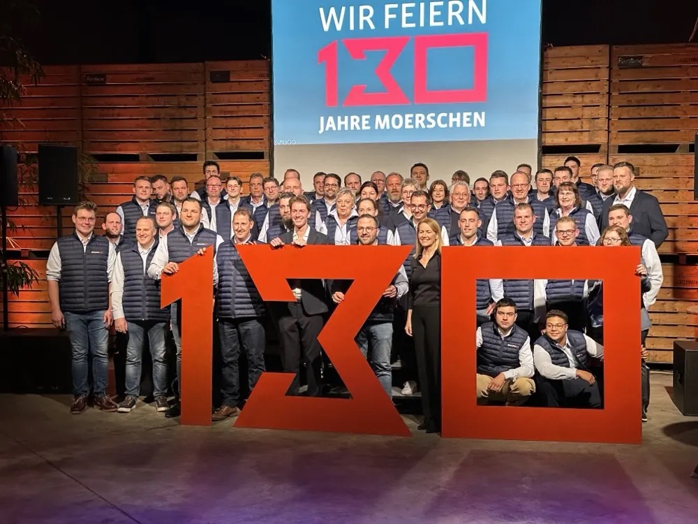 Group photo of the staff in front of the large 130 at the Moerschen anniversary