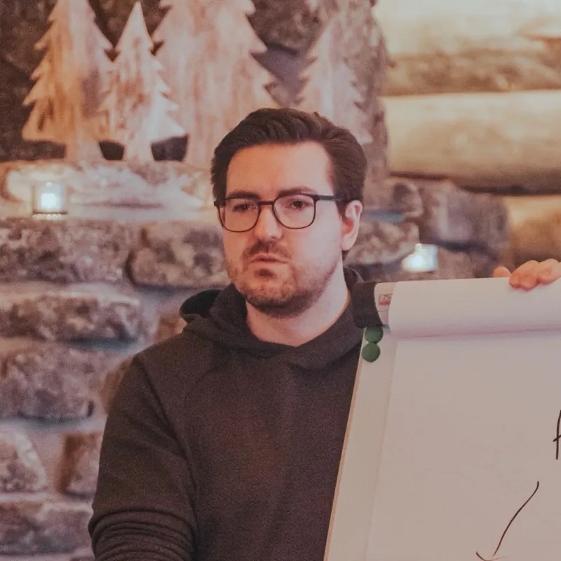 Christian Wenzel drawing on a flipchart in a log cabin