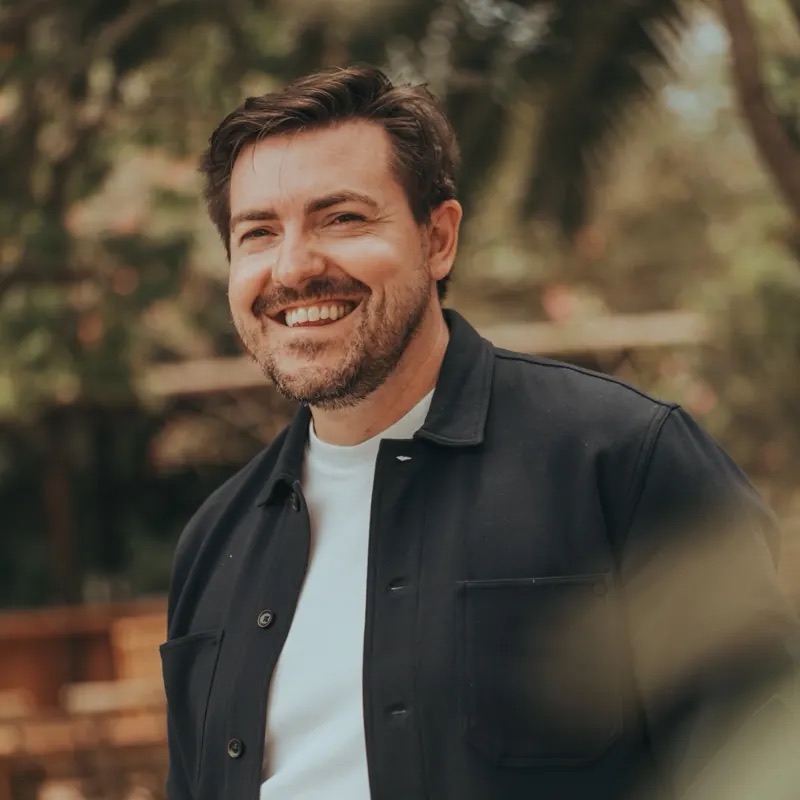 Christian Wenzel lächelt im dunklen Overshirt, draußen im Grünen
